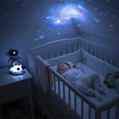 Bébé endormi avec veilleuse projection reflet univers colorée.